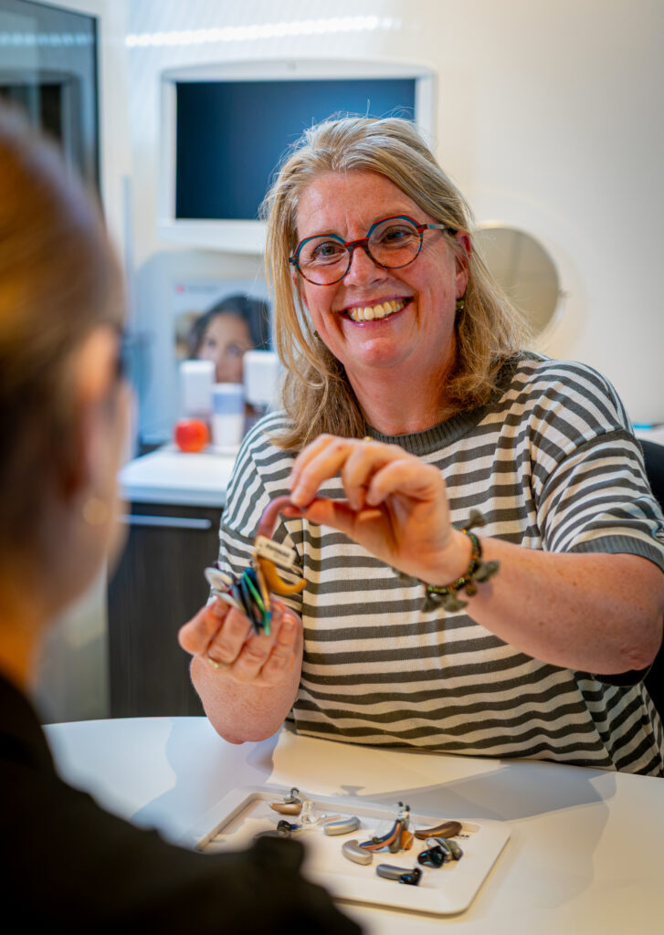 Medewerker van Van Rugge toont een hoortoestel in de winkel in Neede